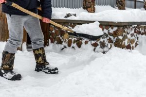 cleaning snow with shovel near house